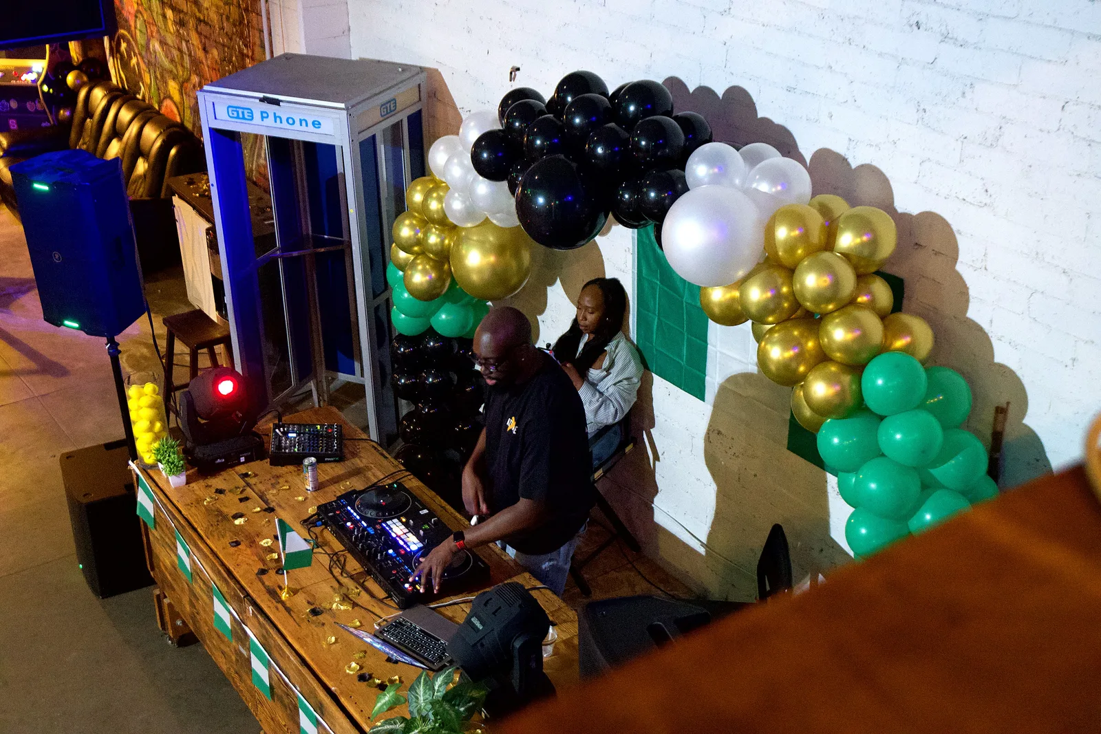 The DJ under a balloon arch at a party in the Back Venue at 1712 Studios